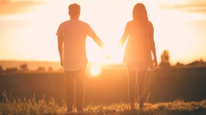 A couple standing hand in hand, bathed in the warm glow of a sunset, symbolizing the belief that sex is a good gift from God, reflecting love, unity, and intimacy.