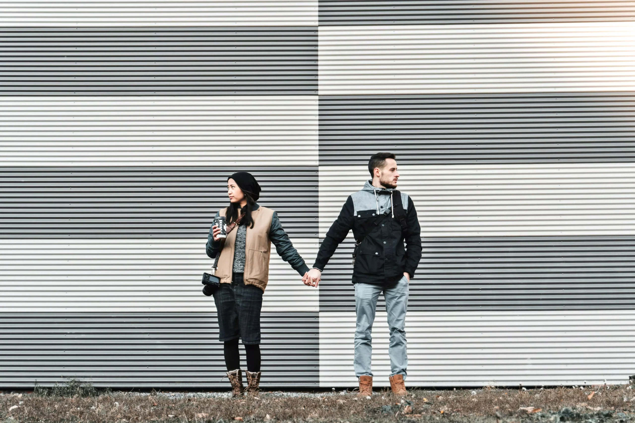 A couple holding hands while looking in opposite directions, symbolizing emotional distance and efforts in avoiding an affair.