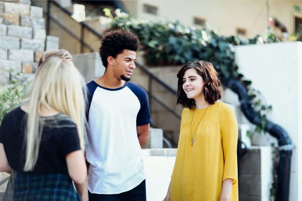 Two teen girls and one teen boy standing and talking