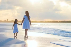 mother and daughter walking on the beach together