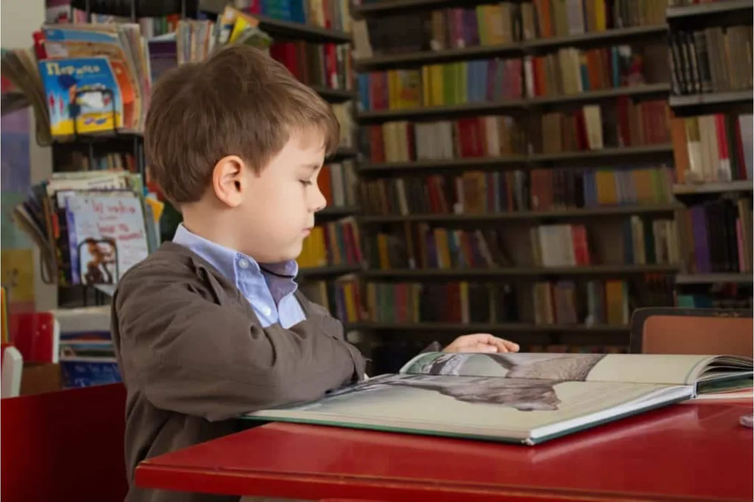 Boy reading a book at a table in a library