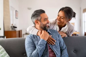 A couple sitting on a couch, encouraging each other with a warm embrace