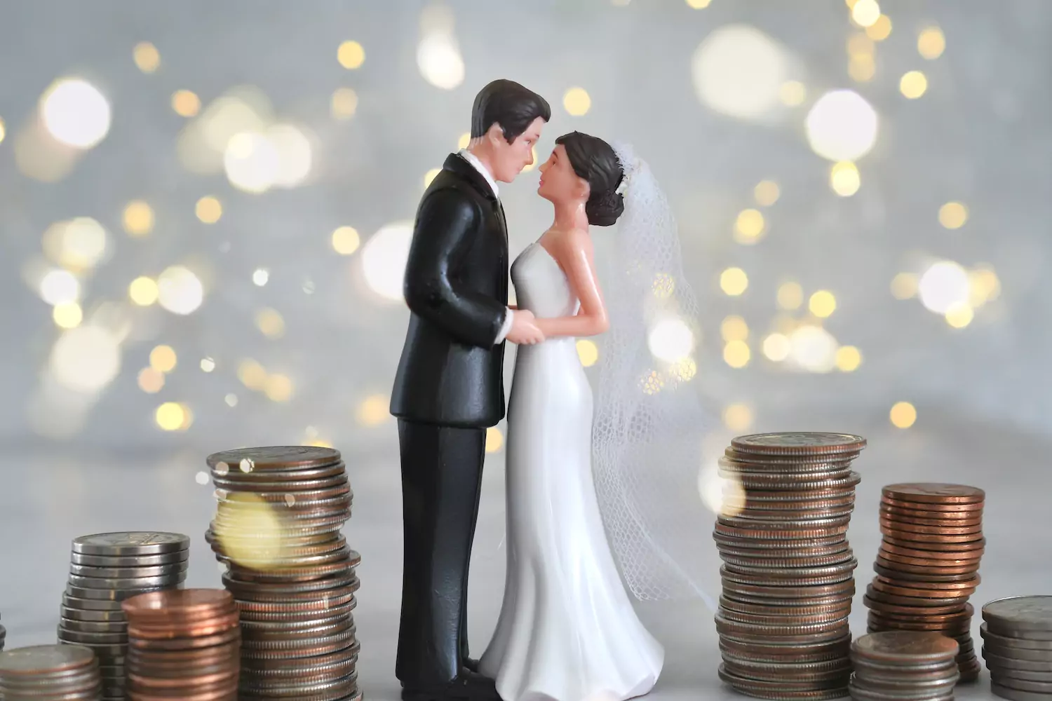 A photo of a little bride and groom plastic pieces standing in a stack of money. Biblical stewardship means we are caretakers of what God has given us. So, when it comes to marriage and money, what does God expect?