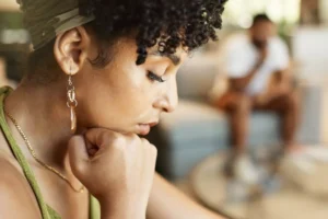 A woman appears deep in thought, with a man blurred in the background, symbolizing the contemplation of what the Bible says about marriage and divorce.