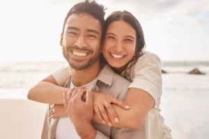 A joyful couple embraces on the beach, symbolizing the importance of being grateful and cherishing each moment together.