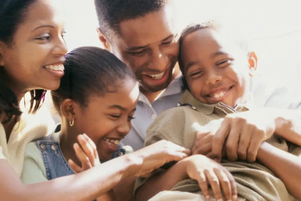 Happy family of four with parents holding smiling young children as they love one another