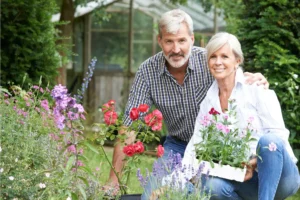 A happy couple gardening together, symbolizing the necessity to prune and make room to grow in marriage as they nurture plants and flowers in a lush outdoor setting.