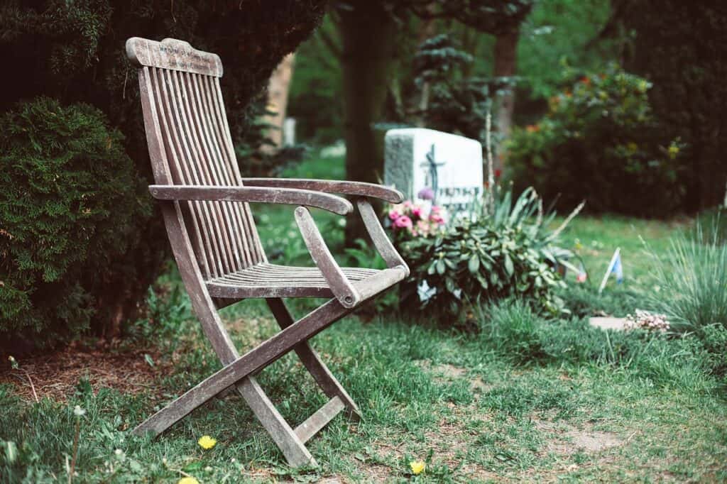 an empty chair sits next to a tombstone