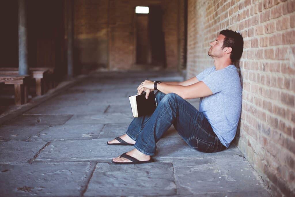 guy with Bible leaning against a wall