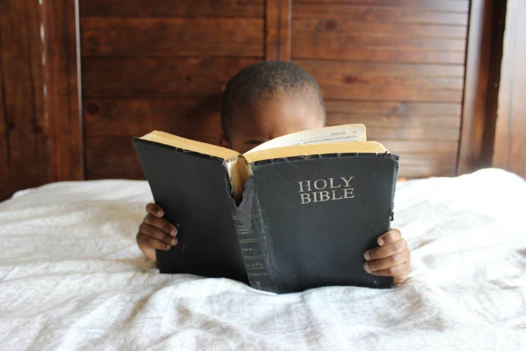 boy in bed reading Bible