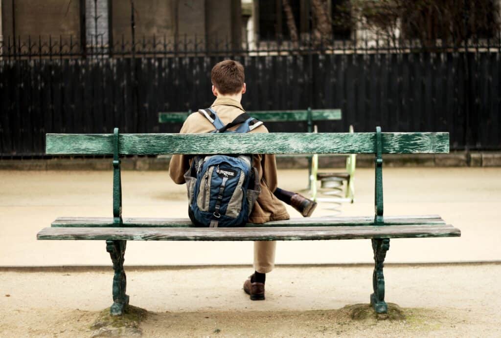 teen guy with backpack sitting on bench