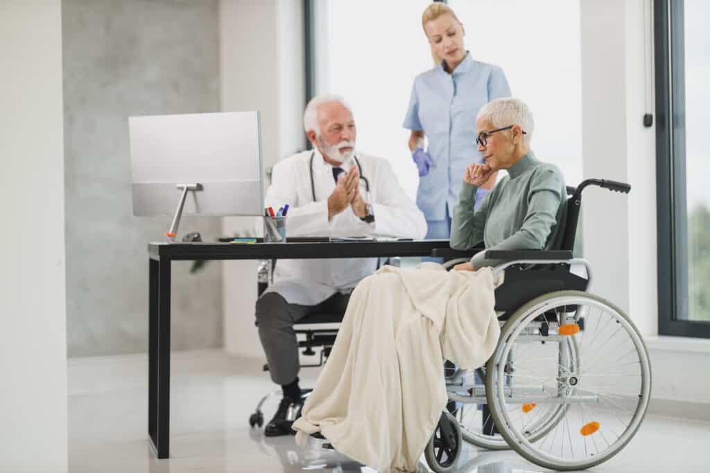 Older woman in wheel chair talking to medical professionals