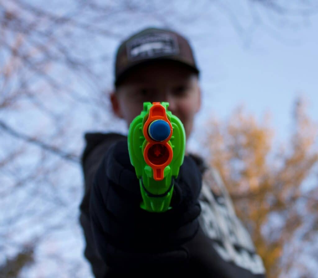 boy pointing nerf gun at camera