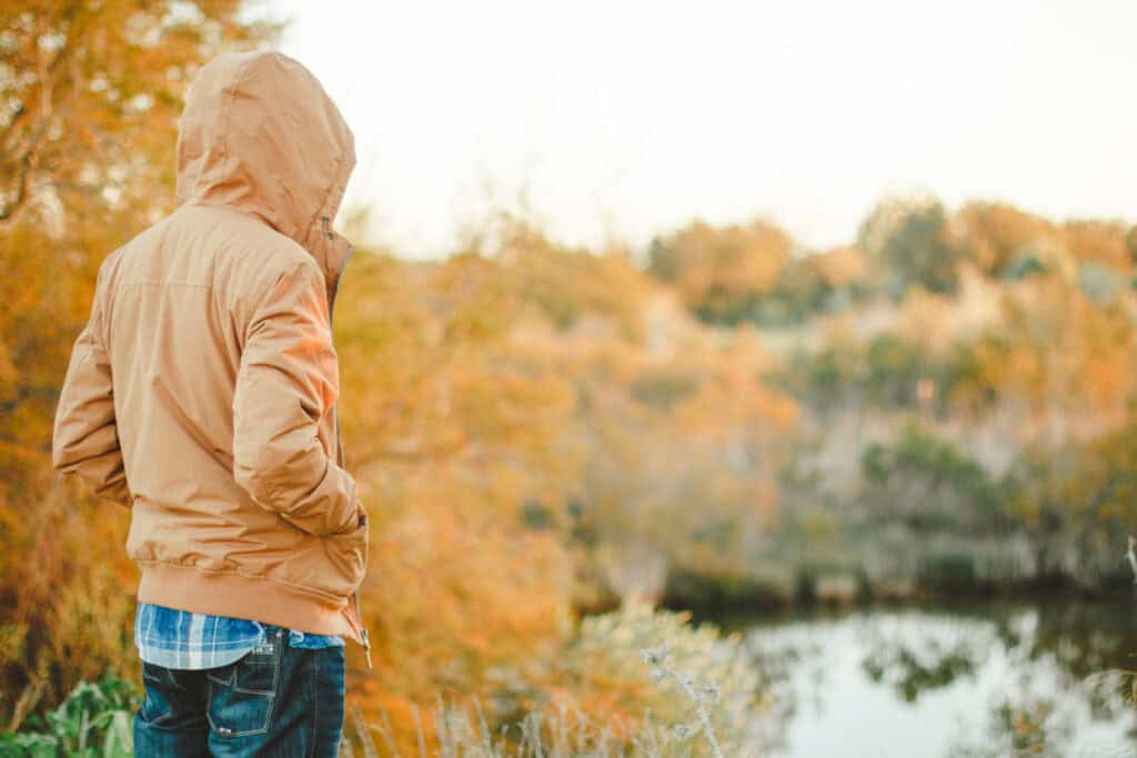 boy in hoodie looking out over lake