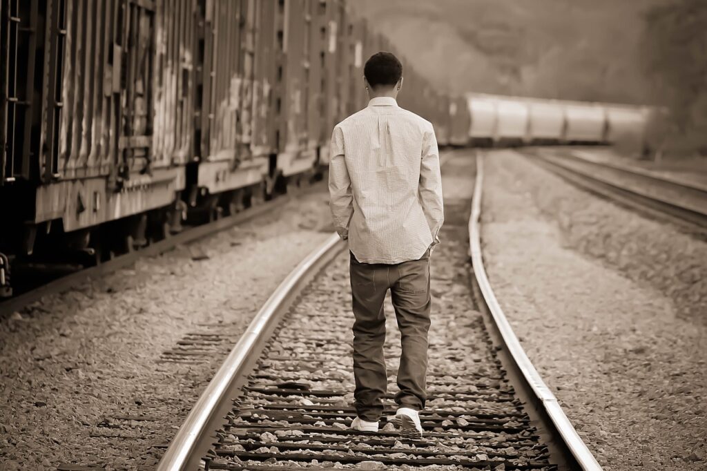 teen guy walking down railroad track