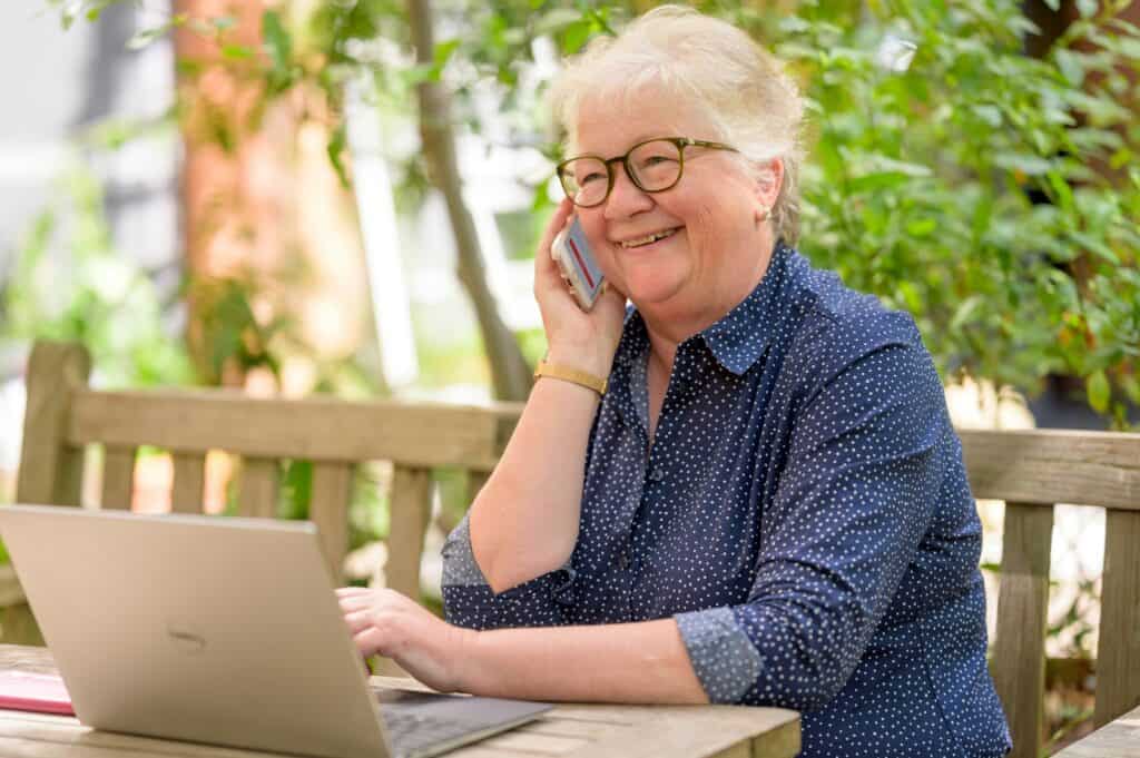 older woman on phone with computer