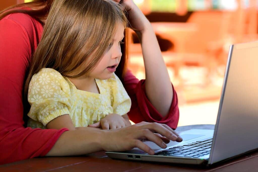 woman holding girl in front of laptop