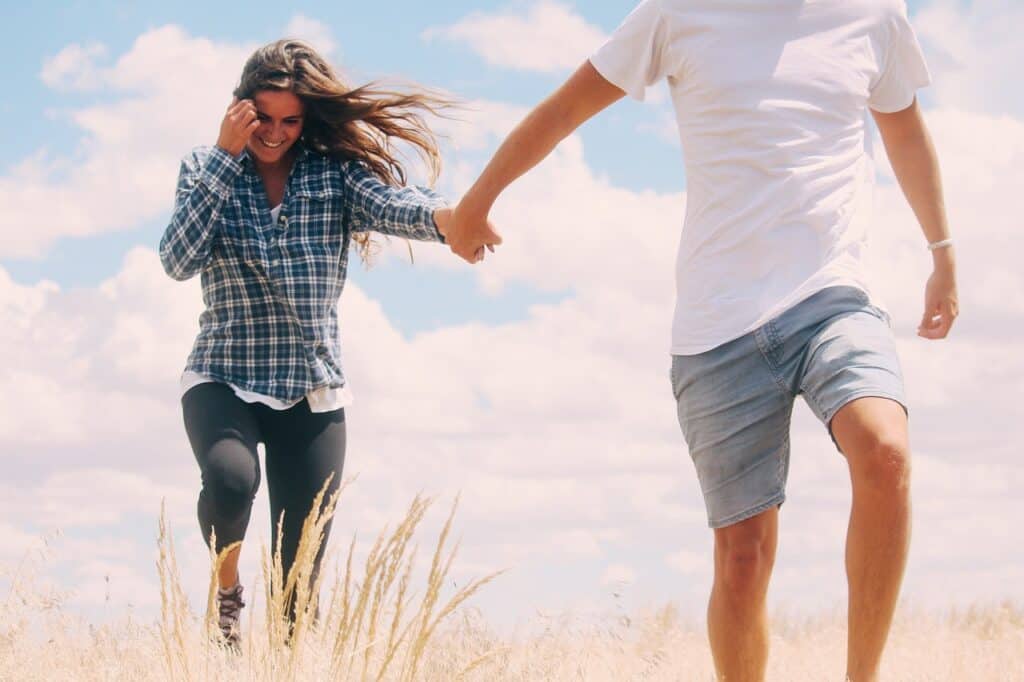 Man holding woman's hand leading her on beach