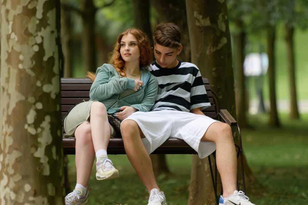 teen couple sitting together on bench