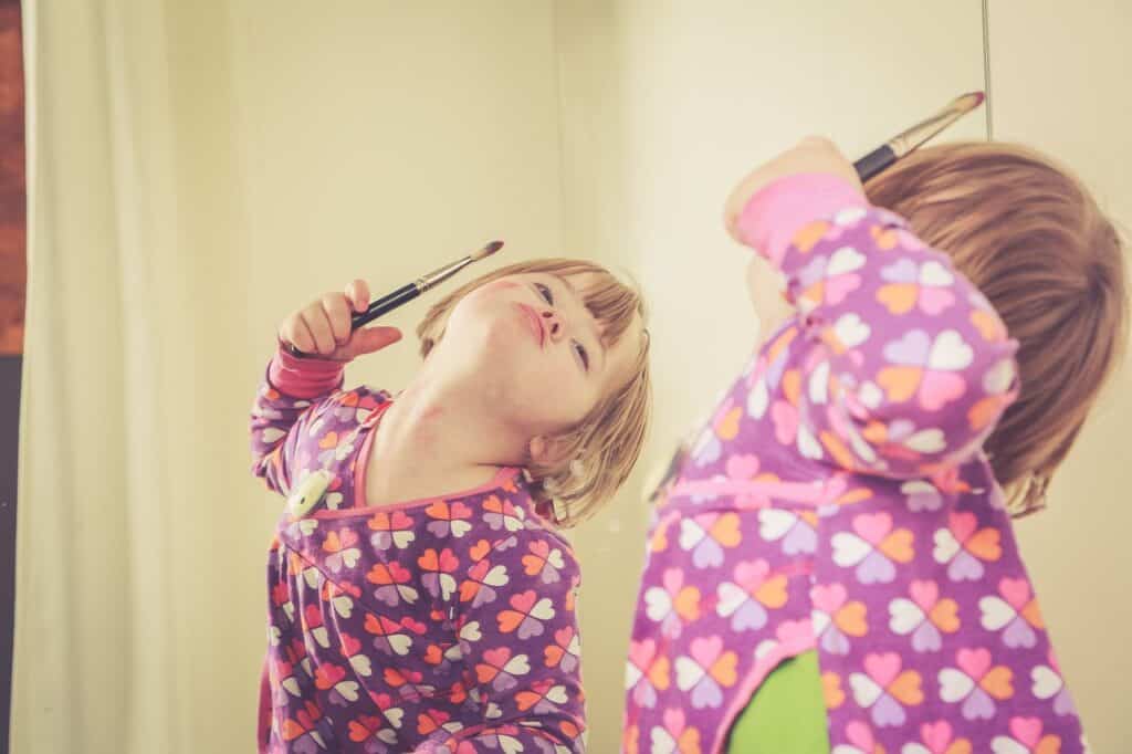 little girl with downs syndrome looking in mirror