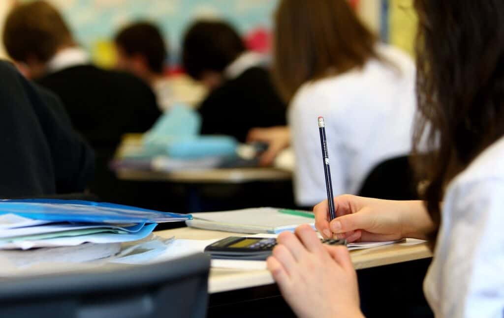 girl in class with pencil and calculator other students in background