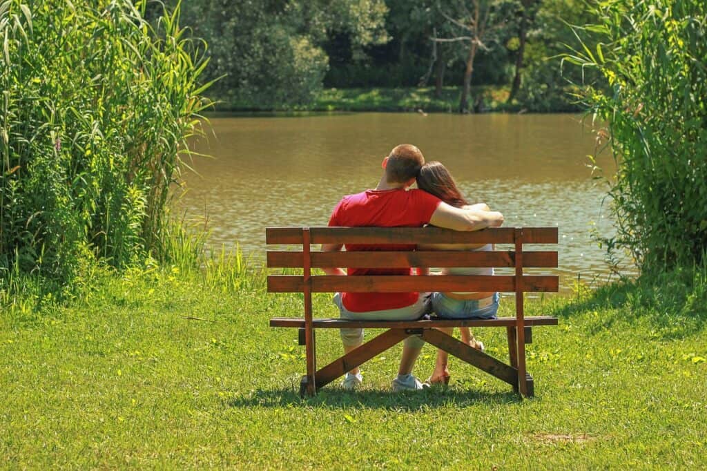 couple sitting on bench by lake