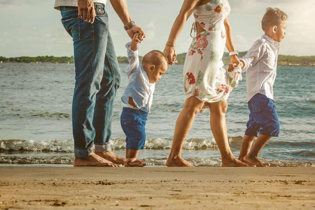 mom dad and two young boys walking on beach