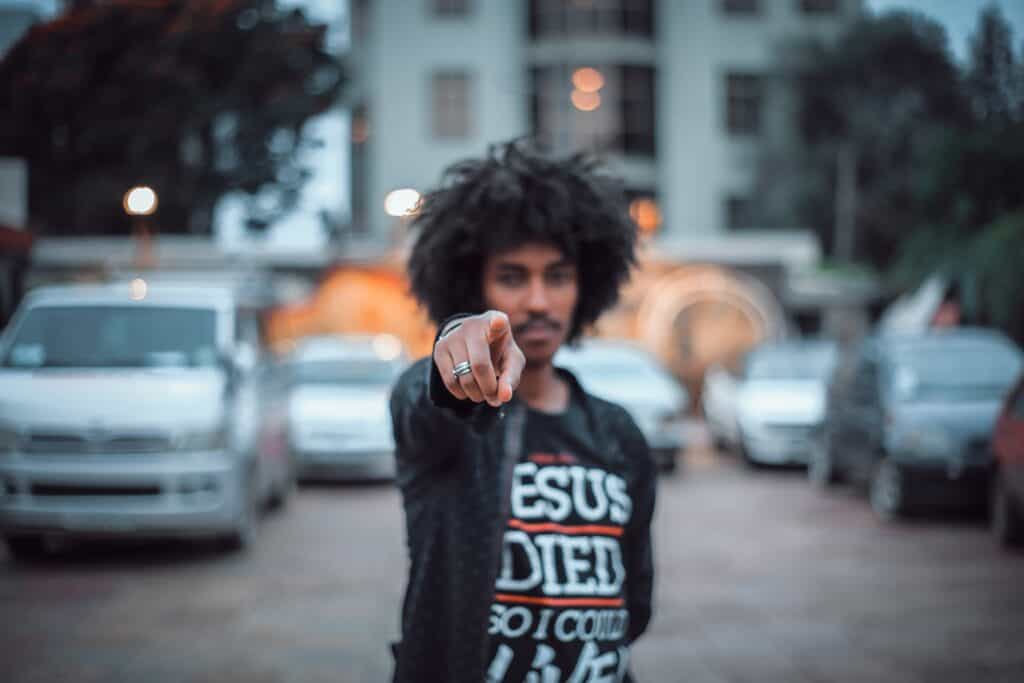 man wearing Jesus died shirt pointing at camera