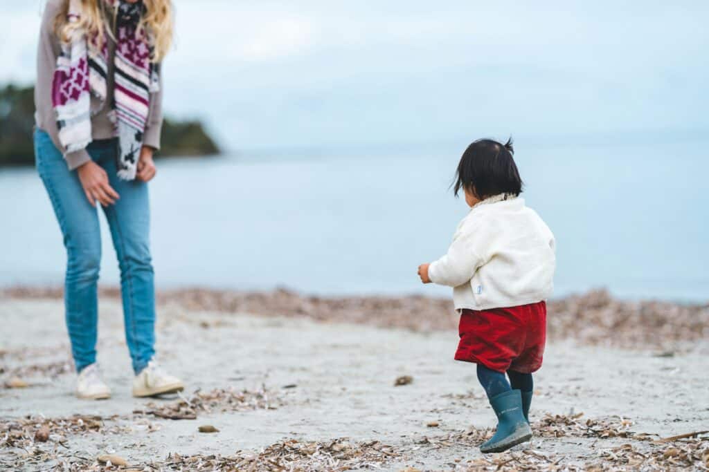 child walking on beach to woman