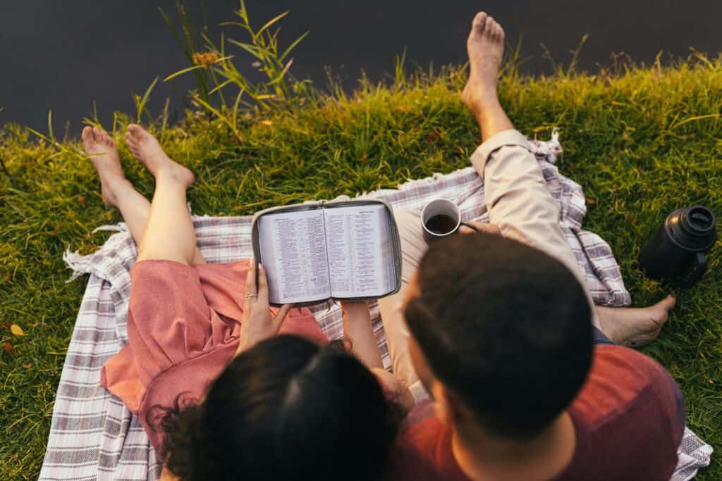 couple sitting on blanket reading Bible