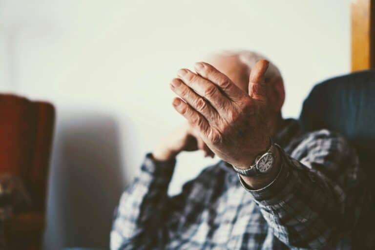 old man sitting beckoning with hand or covering face