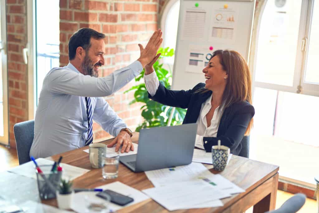 Man and woman working together with computer high five