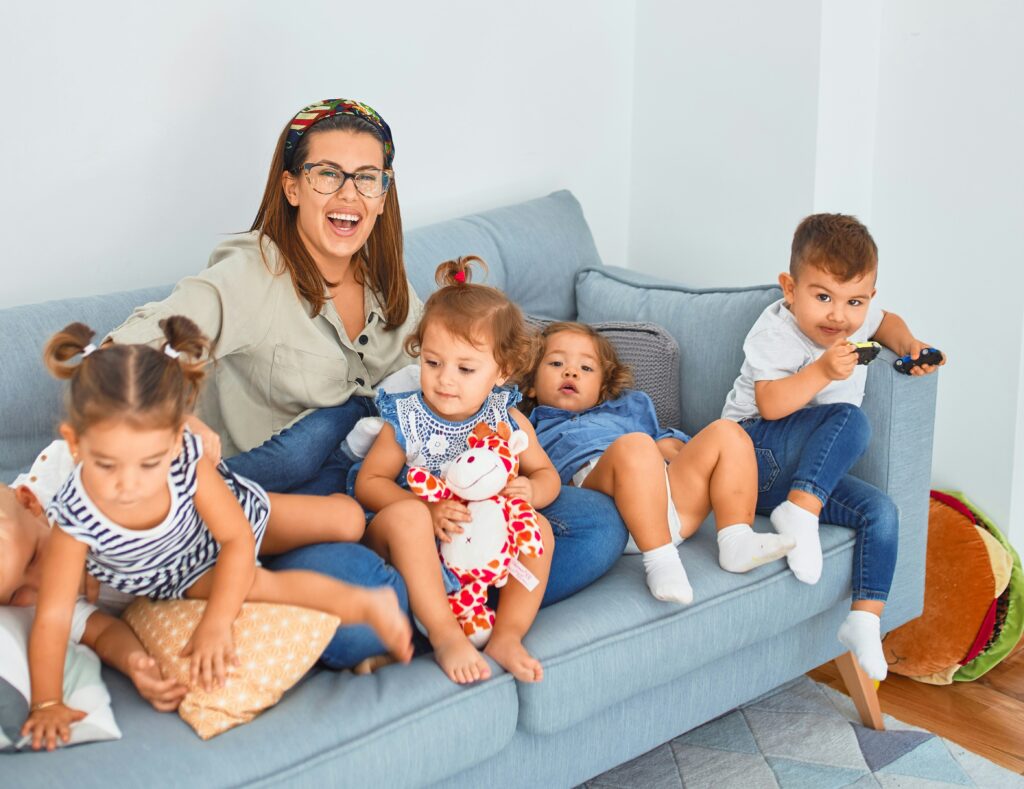 Woman babysitter on couch with 5 young children