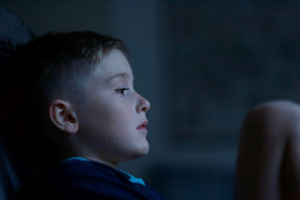 boy sitting in dark looking sad