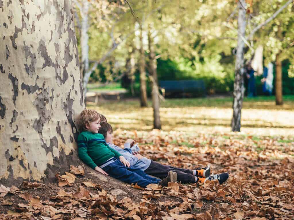 kids sitting lazily by a tree