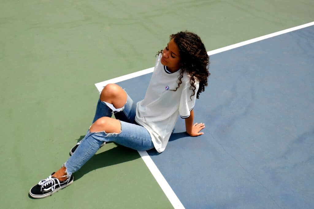 girl sitting on tennis court black fair skinned
