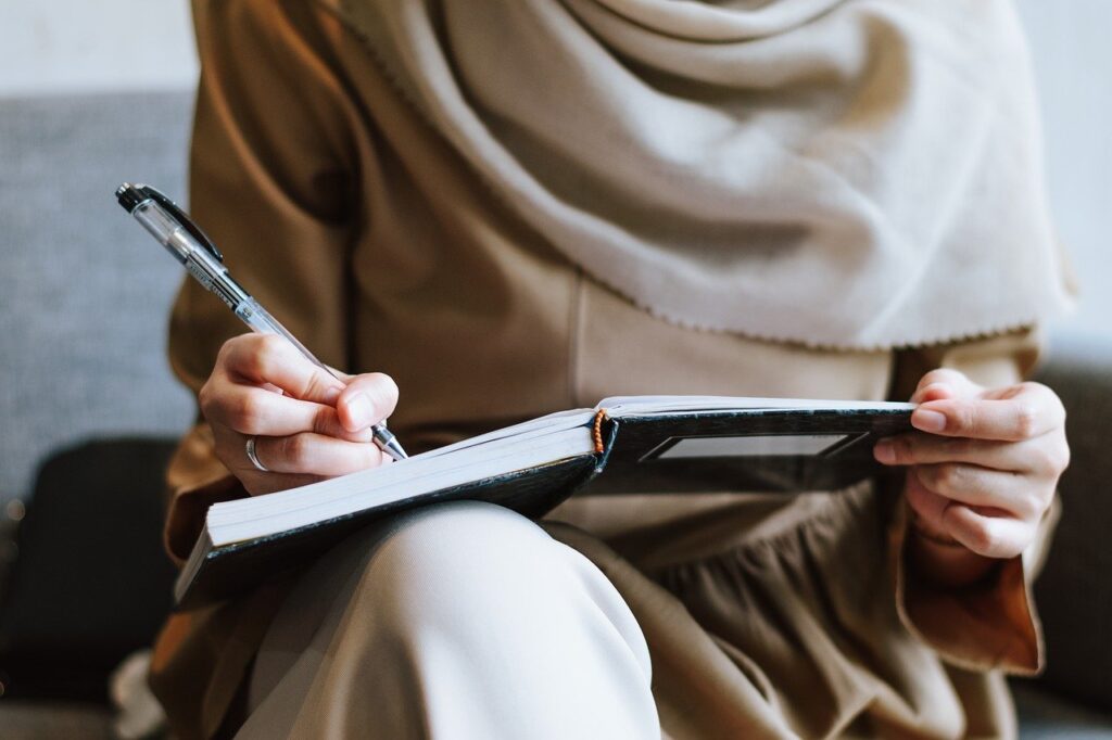 body shot of Muslim woman writing in a journal