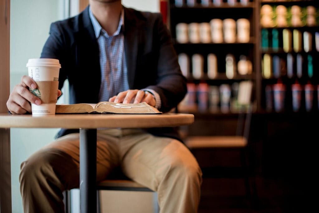 man sitting in shop with coffee and Bible work clothes