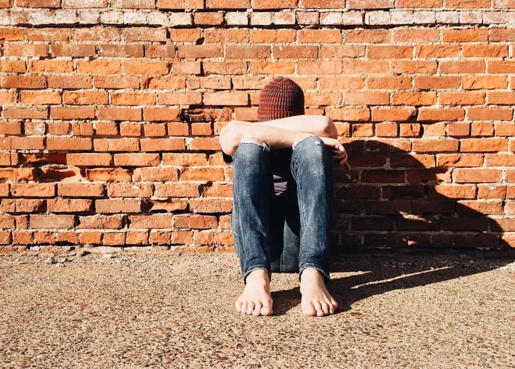 teen guy leaning over on knees looking depressed