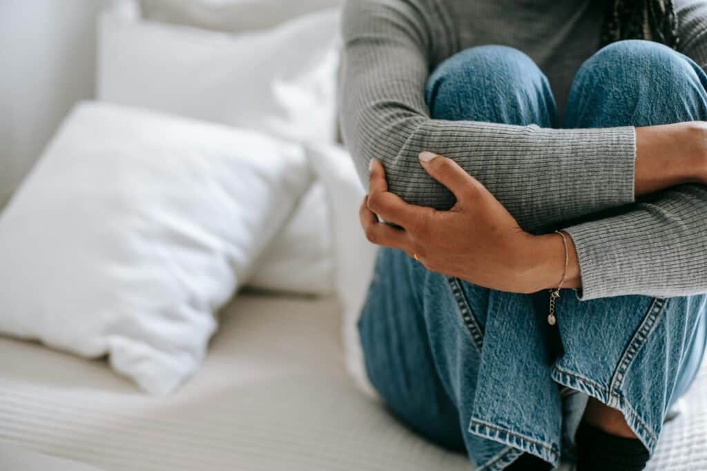 woman sitting on bed arms wrapped around knees