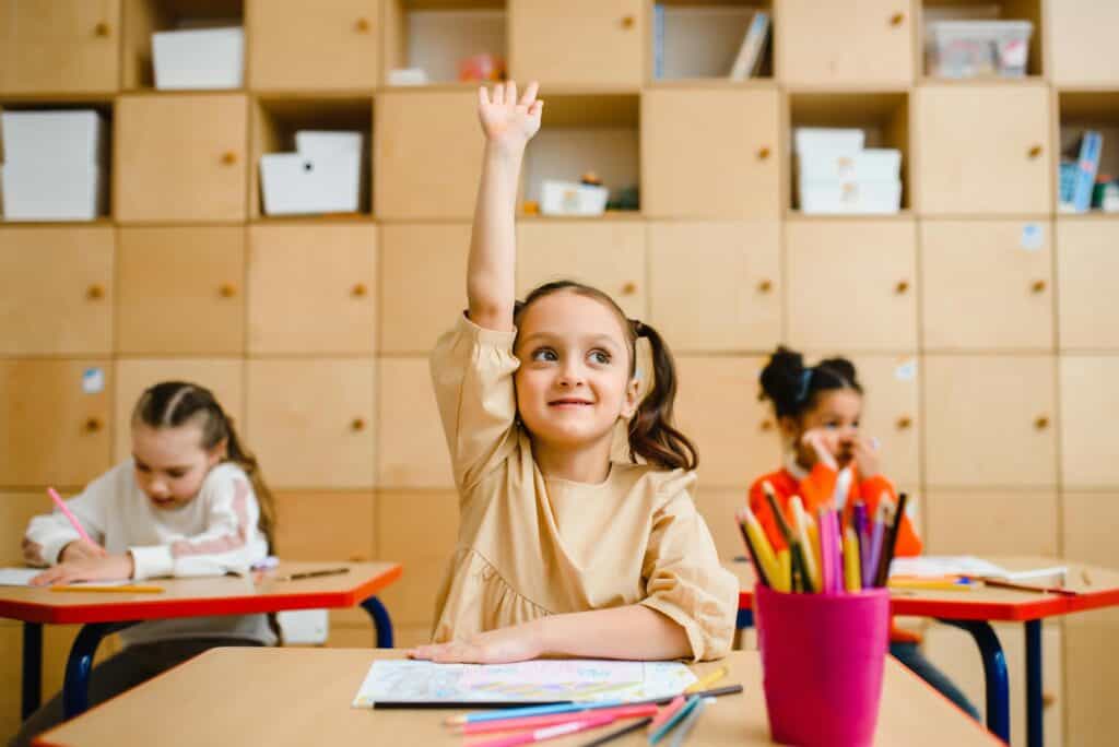 girl in classroom raising her hand