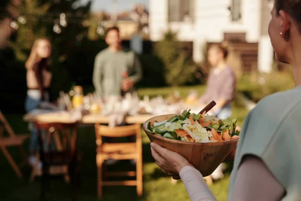 lady bringing salad to table family in background
