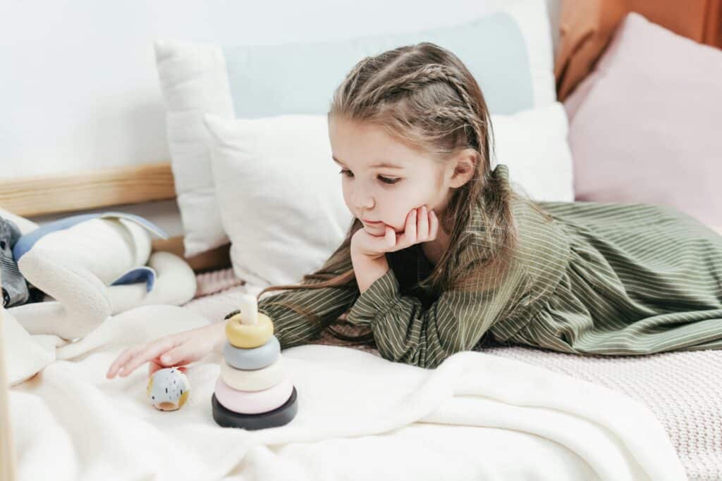 little girl lying on bed looking sad