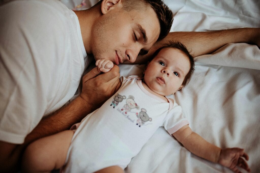 dad lying next to baby on his back