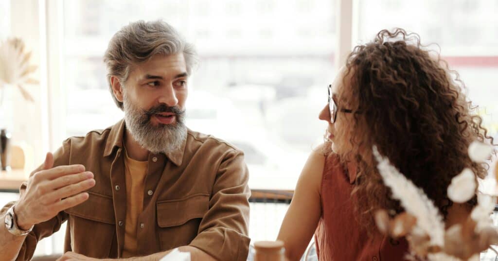 man lifting his hand in explanation to woman couple