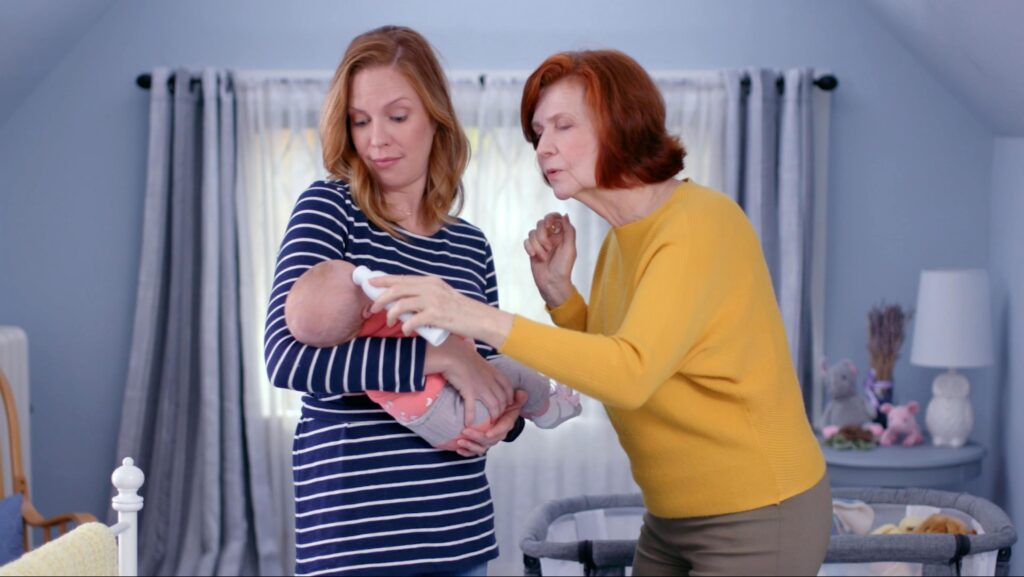 grandma helping mom holding baby