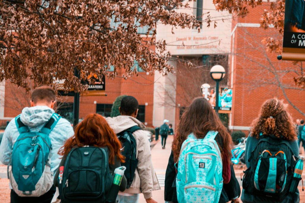 backs of young people in backpacks college