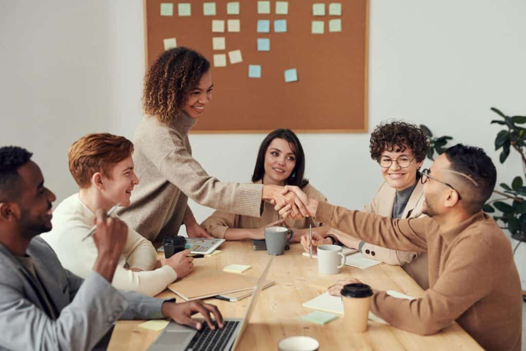 group of coworkers at table man and woman shaking hands meeting