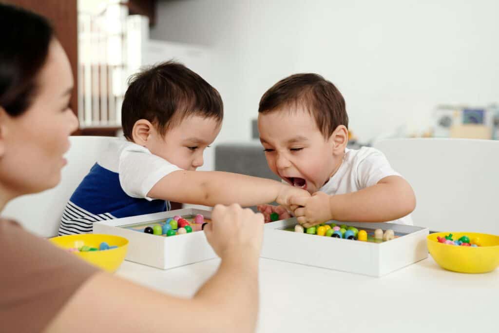 two little boys playing one tries to bite
