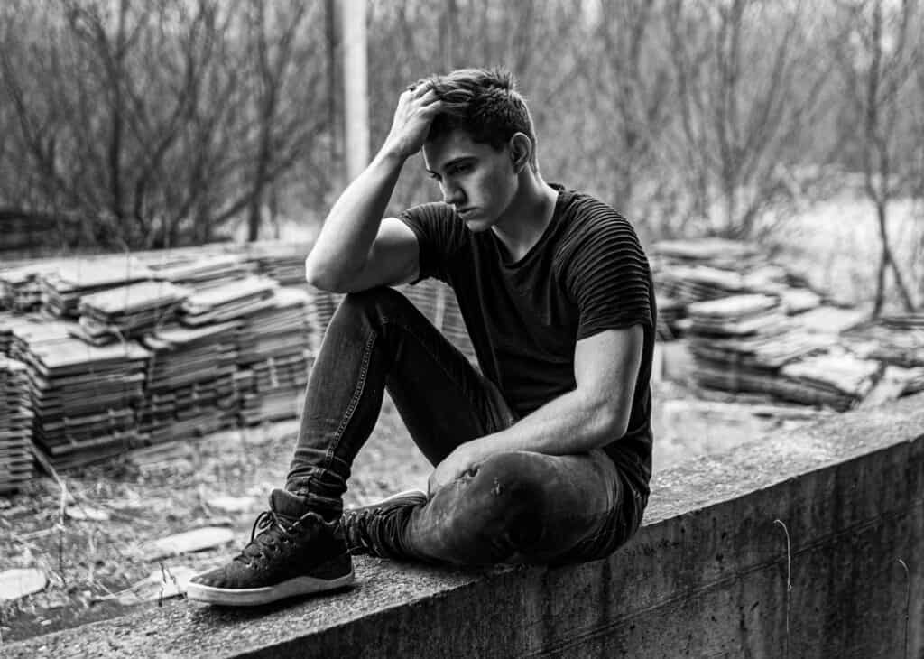black and white teen guy depressed sitting on ledge
